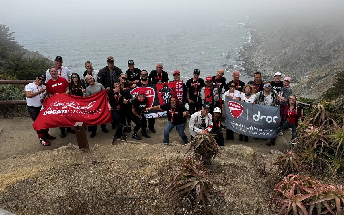Ducati riders regrouped with red Ducati flags on the cliffs at Ragged Point during the coastal group ride